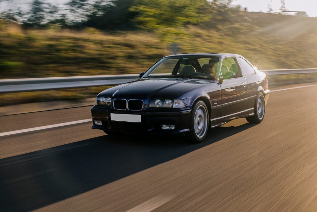 vintage-sedan-car-driving-sunlight-road